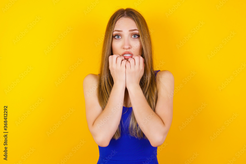 Anxiety - a conceptual image of a beautiful young caucasian woman covering her mouth with her hands and standing outdoors. Scared from something or someone bitting nails. Anxiety - a conceptual image of a beautiful young caucasian woman covering her mouth with her hands and standing outdoors. Scared from something or someone bitting nails.