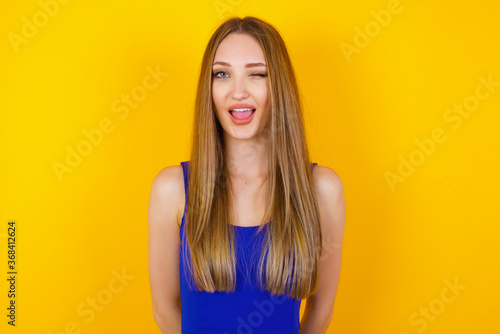 Cute young blonde female blinking her eyes with pleasure having happy expression. Facial expressions and people emotions concept.