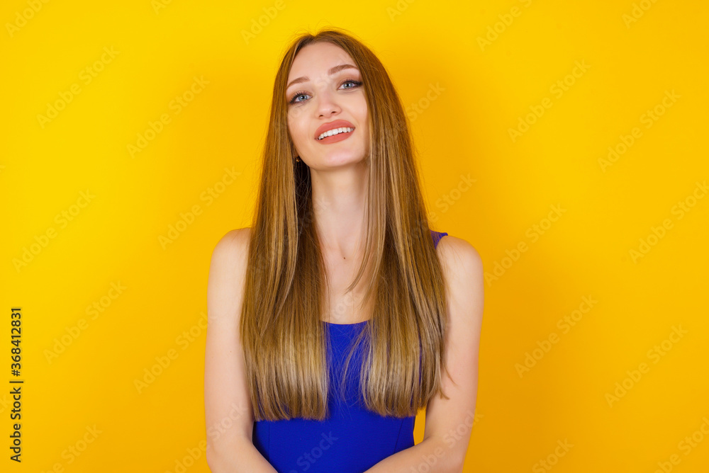 Beautiful smiling brunette female with broad smile, shows white teeth, wears casual t shirt, stands over gray studio wall rejoices having day off. Woman standing indoors. Beautiful smiling brunette female with broad smile, shows white teeth, wears casual t shirt, stands over gray studio wall rejoices having day off. Woman standing indoors.