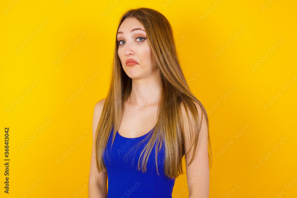 Beautiful woman with snobbish expression curving lips and raising eyebrows, looking with doubtful and skeptical expression, suspect and doubt. Standing indoors over gray background. Beautiful woman with snobbish expression curving lips and raising eyebrows, looking with doubtful and skeptical expression, suspect and doubt. Standing indoors over gray background.