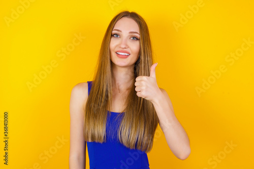 Good job! Portrait of a happy smiling blue eyed young successful woman giving thumb up gesture standing outdoors. Positive human emotion facial expression body language. Funny girl
