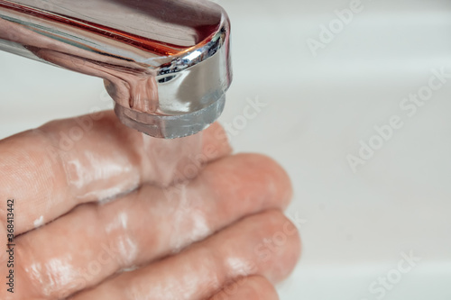 Close-up of a man's hand under a stream of clean water from a tap, copy space