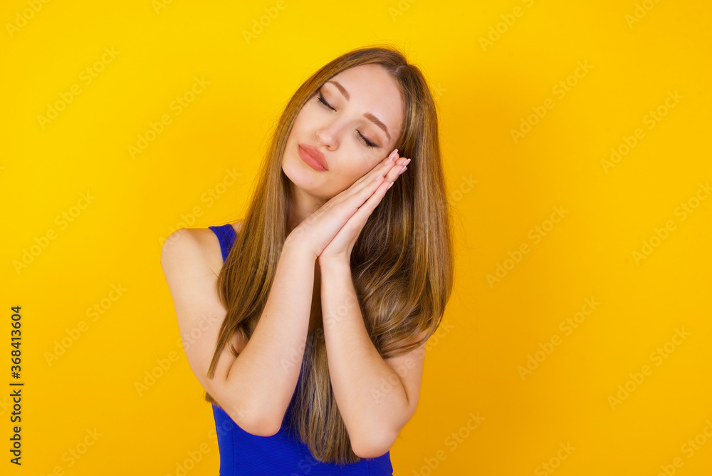 Relax and sleep time. Tired beautiful dark haired girl with closed eyes leaning on palms as pillow pretending sleeping being exhausted seeing dreams standing against gray background. Sleeping gesture. Relax and sleep time. Tired beautiful dark haired girl with closed eyes leaning on palms as pillow pretending sleeping being exhausted seeing dreams standing against gray background. Sleeping gesture.