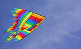 colorful kite flies high in the blue sky