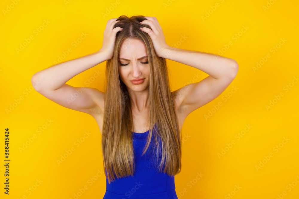 Young beautiful woman holding her head over isolated background suffering from headache desperate and stressed because pain and migraine. Hands on head.