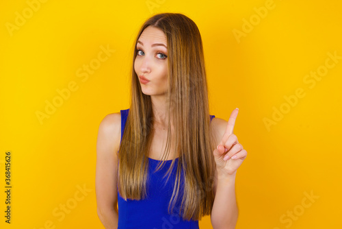 Woman gesturing a no sign. Closeup portrait unhappy  serious girl raising finger up saying  oh no you did not do that. Standing over yellow background. Negative emotions facial expressions  feelings.