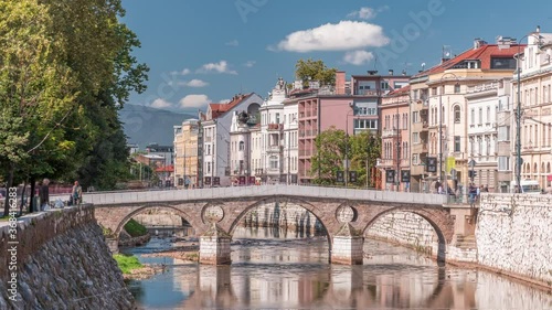 View of the Latin bridge timelapse, one of the oldest bridges of Bosnia and Herzegovina, runs through the Milyacka River in Sarajevo at sunny day photo