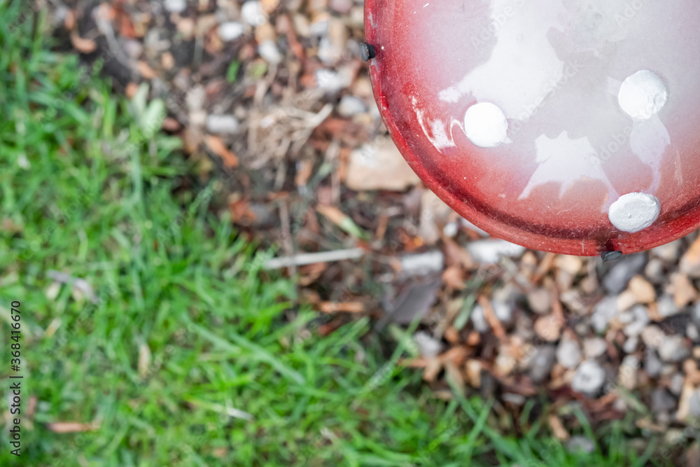 Shallow focus of a home-made, ornate glass mushroom seen installed into a gravel, adjacent to a lawned area. Shallow focus of a home-made, ornate glass mushroom seen installed into a gravel, adjacent to a lawned area.