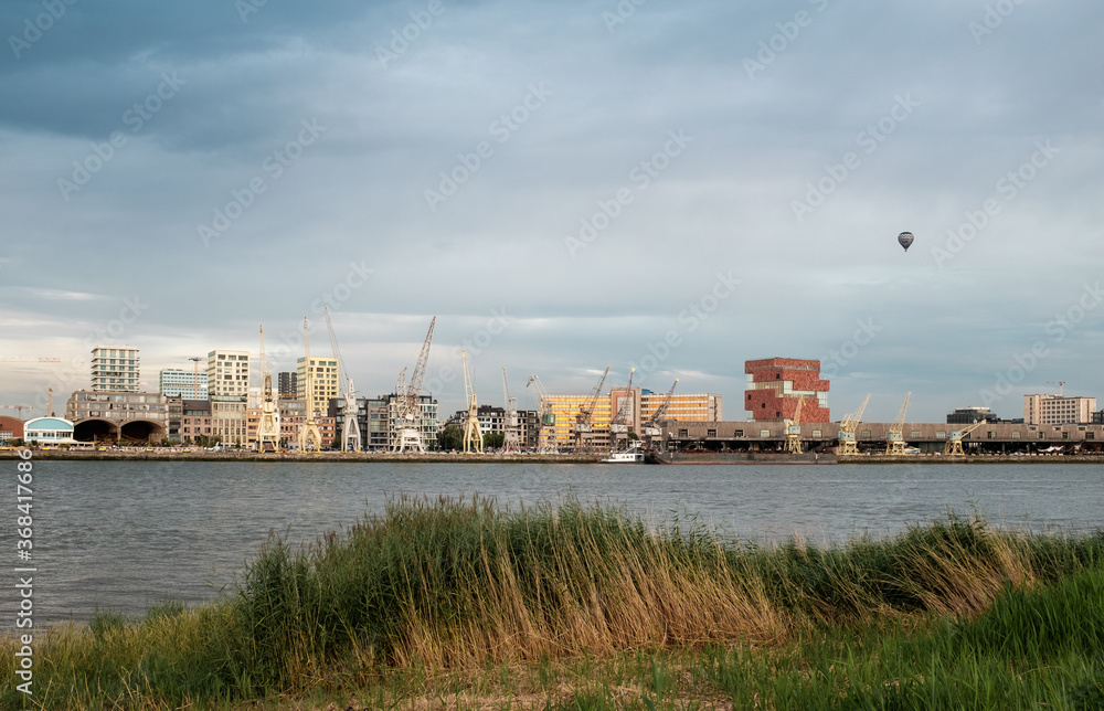 Skyline of Antwerp across the river Scheldt with view on old harbour cranes