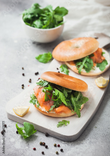Fresh sandwiches with salmon and bagel, cream cheese and wild rocket in white bowl on light table