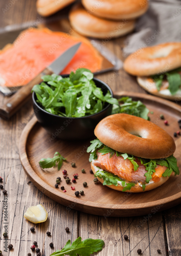 Fresh healthy organic sandwich with bagel and salmon, cream cheese and wild rocket in bowl with bread and smoked salmon pack.