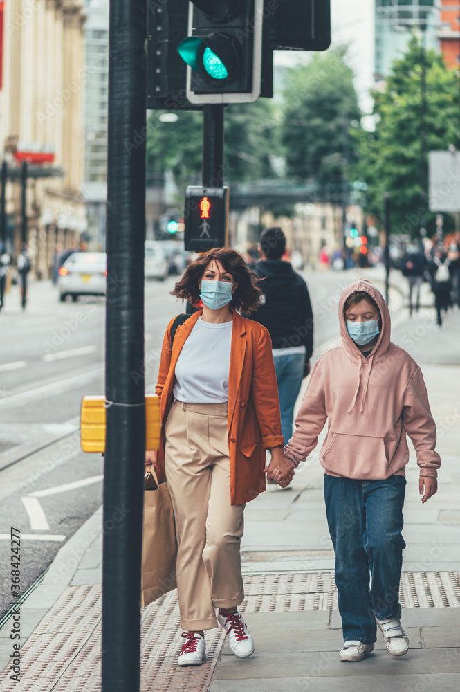 Mum and daughter in face mask are shopping in city centre of MANCHESTER, ENGLAND, UK , new normal