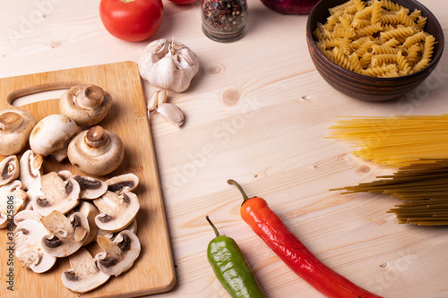 raw champignon mushrooms and tomatoes on the rustic wooden surface