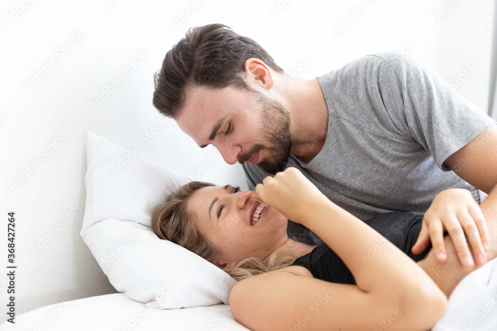 Caucasion couple feeling happy on bed in bedroom