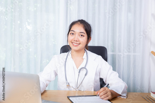 female doctor sit on her desk in the office focus on her job on laptop and smile