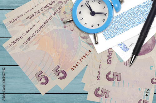 5 Turkish lira bills and alarm clock with pen and envelopes. Tax season concept, payment deadline for credit or loan. Financial operations using postal service photo