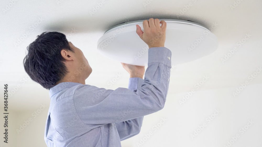天井にシーリングライトをつける男性