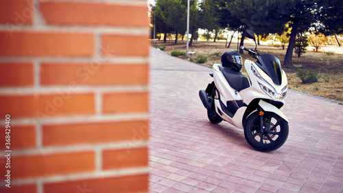 White motorcycle with a brick wall on the side of the image.