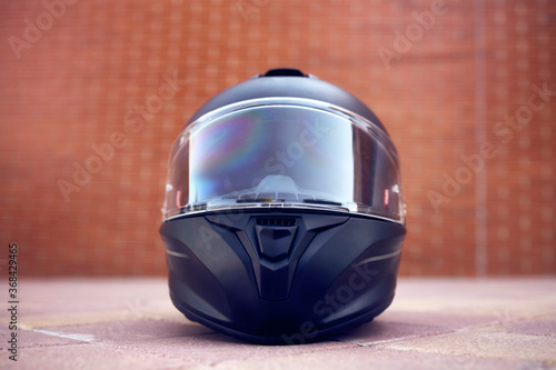 Close-up of a black helmet on the ground with the visor closed. Front view.