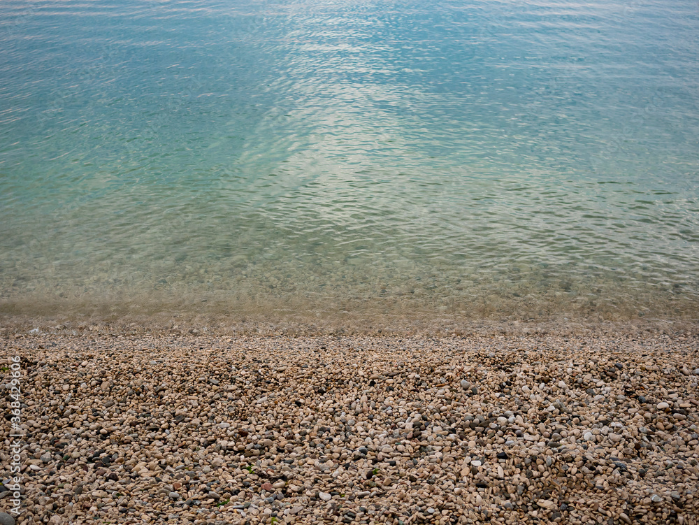 beautiful seashore made of stones. Pebble beach. Turquoise water. Blue ocean. Summer