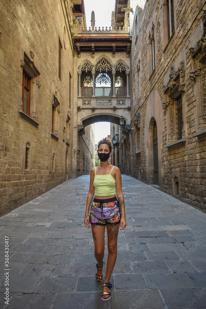 Woman wearing a surgical mask, walking the empty streets of Barcelona during the coronavirus.