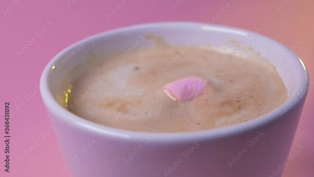 Delicious fresh hot chocolate with marshmallows. Little soft pink marshmallow throwing in cacao purple cup isolated on background. Hot beverage. Winter time. Delicious fresh hot chocolate with marshmallows. Little soft pink marshmallow throwing in cacao purple cup isolated on background. Hot beverage. Winter time.