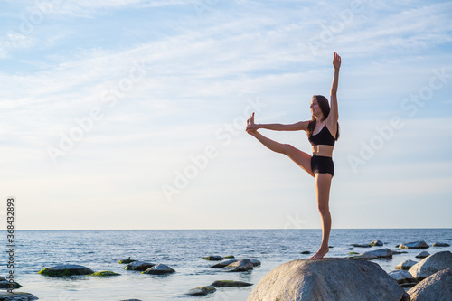 Woman standing in Hand to Toe pose near sea
