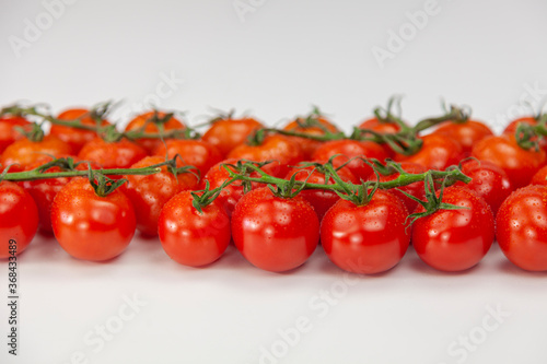 Fresh cherry tomatoes on branch on white background. © Regisser.com