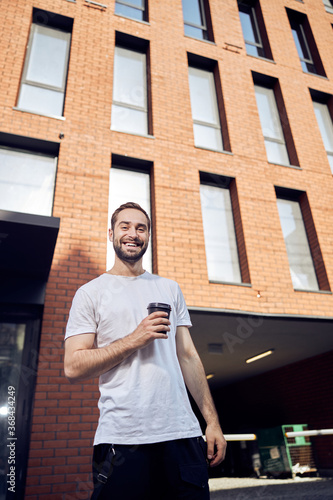 Waist up portrait of smiling young man with coffee ouydoors photo