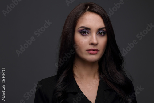 Portrait of a beautiful woman in a black jacket on a gray background