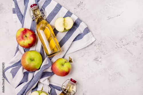 Bottles of Apple Vinegar and Ripe Apples on Kitchen Towel Light Gray Background Flat Lay Copy Space Apple Cider