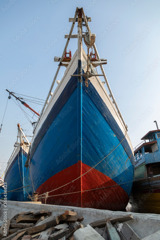 The bow of a huge old wooden boat in the port of the city of Jakarta