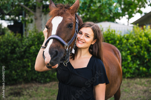 Portrait of a young beautiful woman with his animal friends - Millennial having fun after a riding lesson with a horse in a field