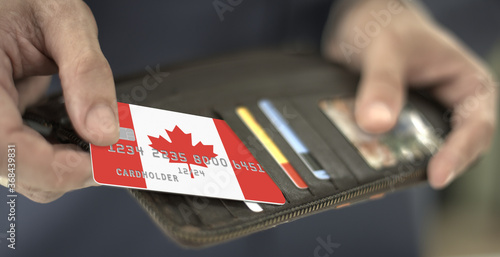 Man pulls plastic bank card with flag of Canada out of his wallet, fictional card number