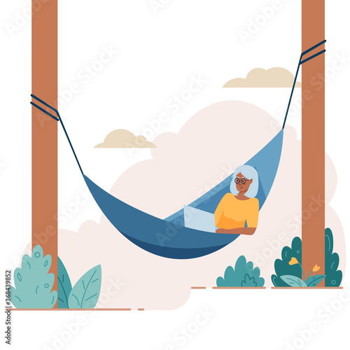Senior elderly woman lies with laptop on hammock