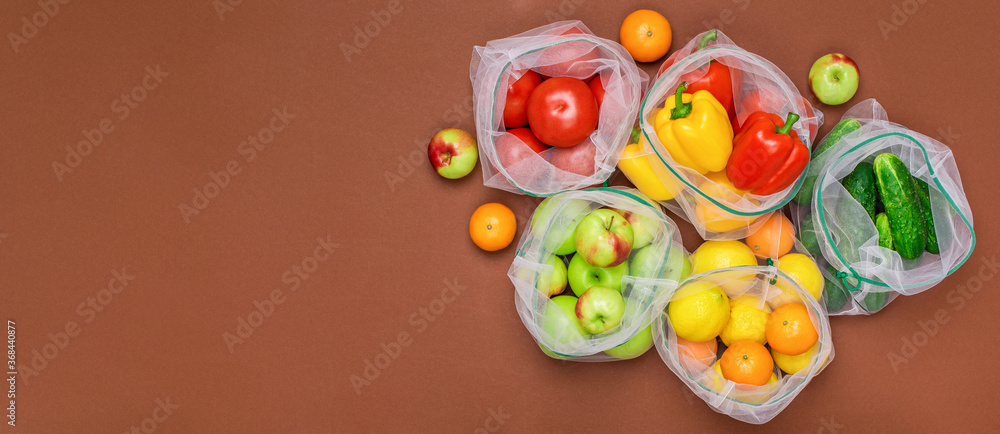 Wide banner Fresh and juicy fruits and vegetables in reusable eco friendly mesh bags on the brown background. Plastic free, zero waste, and sustainable living concept. Reusable using. Copy space. Wide banner Fresh and juicy fruits and vegetables in reusable eco friendly mesh bags on the brown background. Plastic free, zero waste, and sustainable living concept. Reusable using. Copy space.