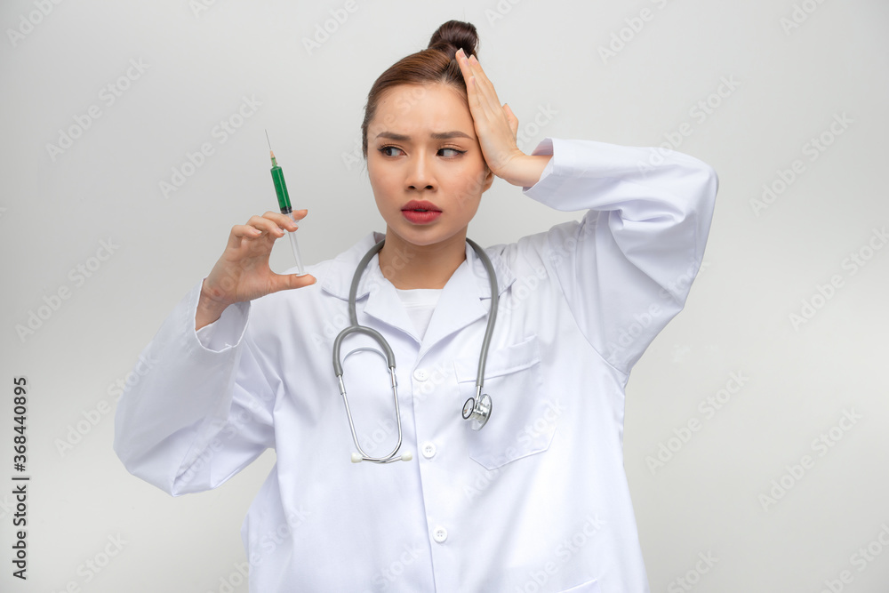 Professional doctor woman holding syringe with medical vaccine stressed with hand on head, shocked with shame and surprise face Professional doctor woman holding syringe with medical vaccine stressed with hand on head, shocked with shame and surprise face