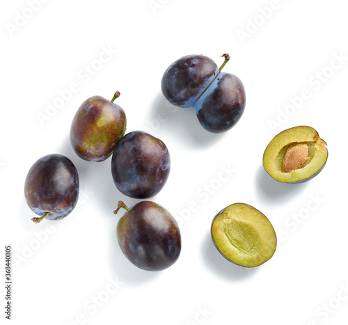 ripe whole blue plum, broken in half with a bone. Fruit isolated on white background