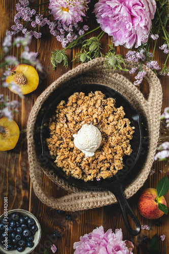 Blueberry and peaches crispy oatmeal crumble with ice cream, wooden table