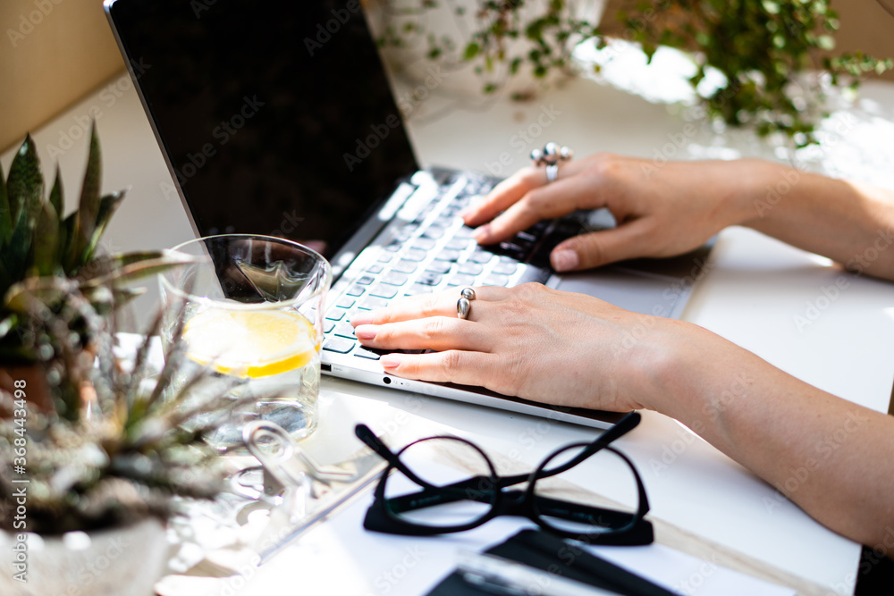 Fototapeta premium Woman's hands on laptop keyboard, cozy workplace