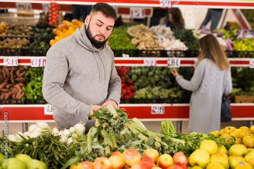 Adult man is choosing leek and celery in the grocery store. High quality photo