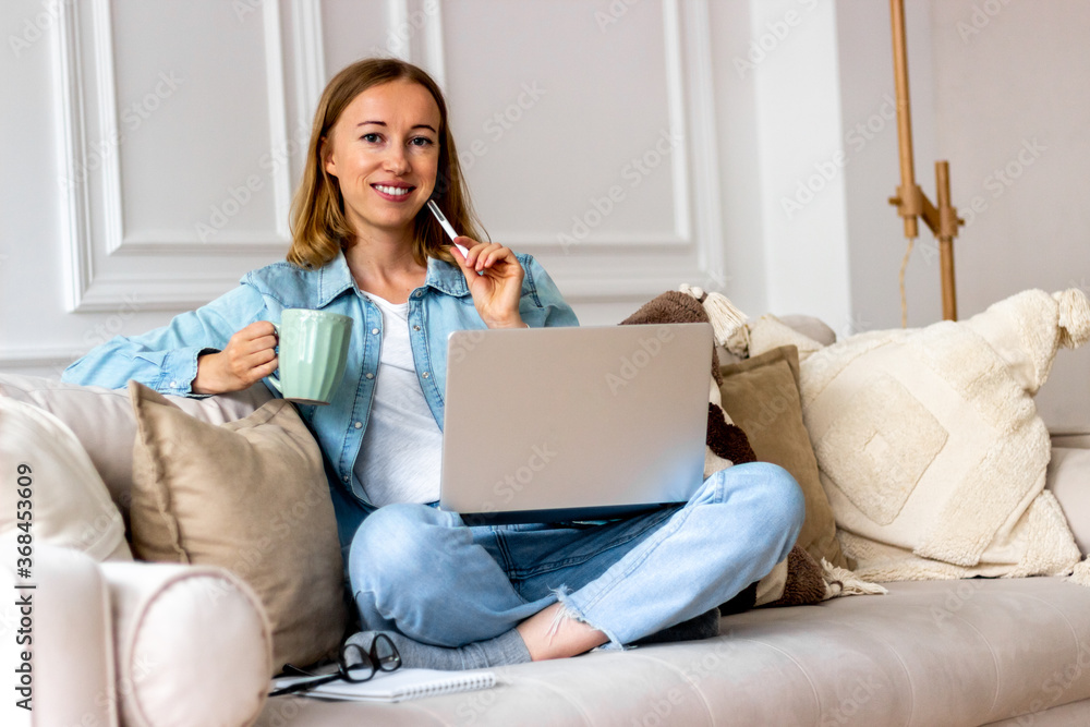 Happy woman on sofa with laptop working at home Happy woman on sofa with laptop working at home