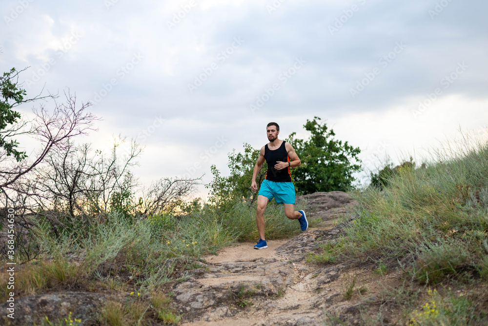 Fototapeta premium Male runner running over stones, copy of free space.