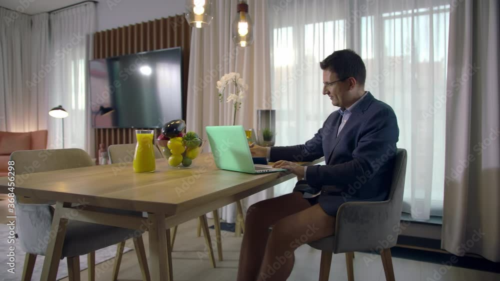 Slow-mo: Focused Handsome Caucasian Man Dressed in a Jacket and Underwear Videoconferencing At Home In A Modern Apartment Using His Laptop Slow-mo: Focused Handsome Caucasian Man Dressed in a Jacket and Underwear Videoconferencing At Home In A Modern Apartment Using His Laptop