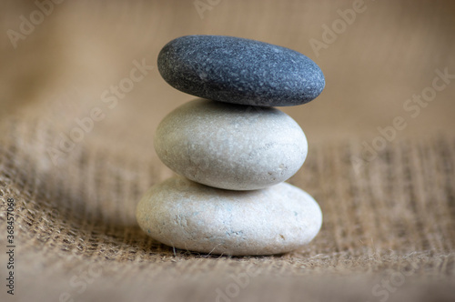 One simplicity stones cairn on jute brown background, group of five light and dark gray pebbles built in tower