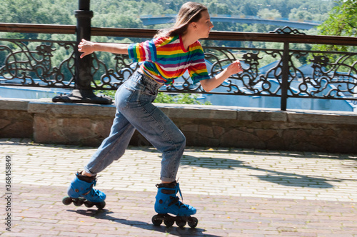 Canvas-taulu Cheerful beautiful teenage girl rollerblading in the park on a warm summer morni