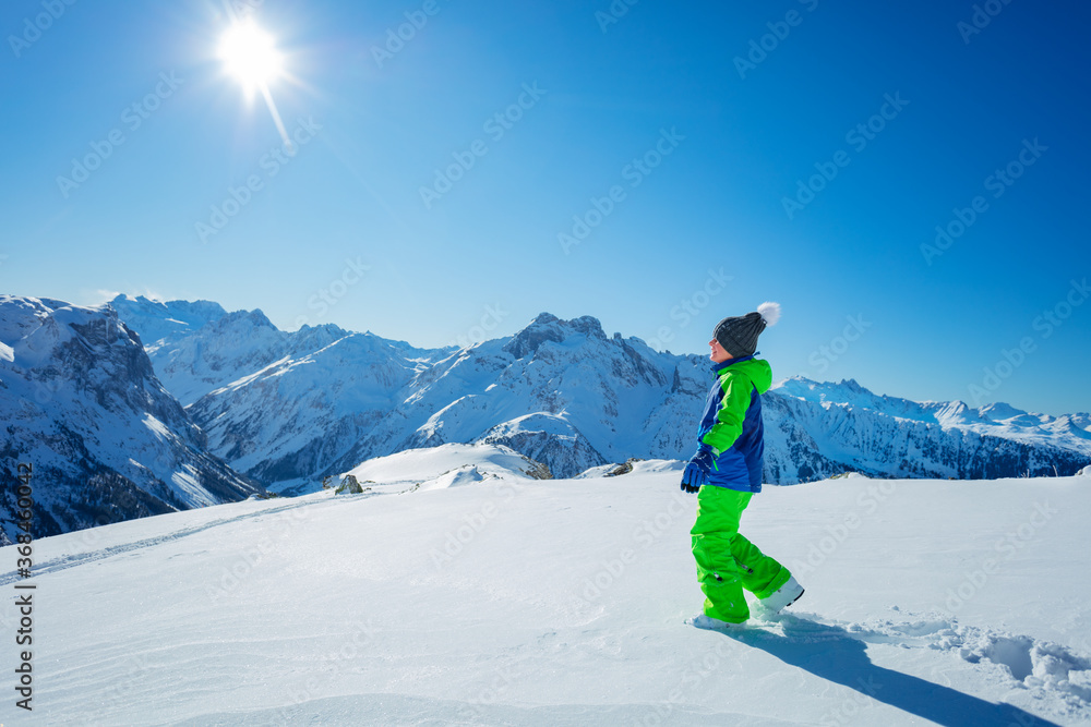 Boy in hiking school stepping on virgin snow enjoying summit view winter activity concept