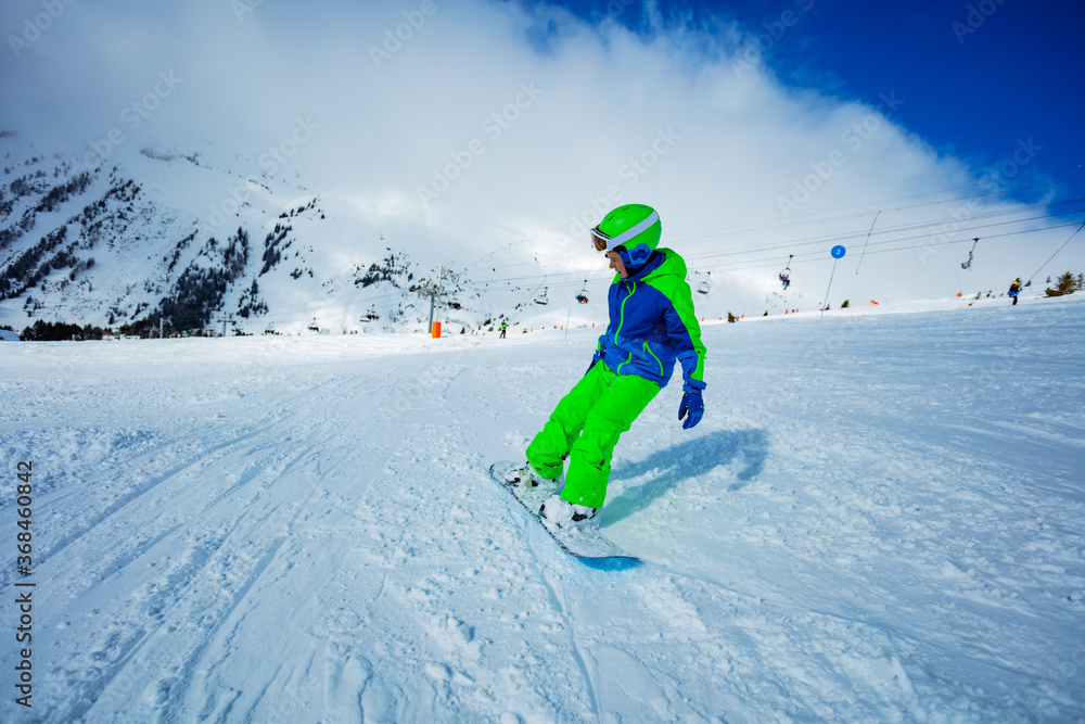 Motion portrait of a boy on snowboard ride downhill view from behind on the slope track