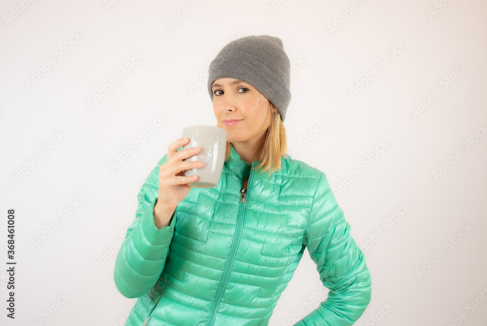 Beautiful woman with winter clothes picking up a cup Beautiful woman with winter clothes picking up a cup