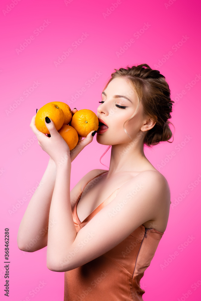 elegant beautiful blonde woman licking ripe oranges isolated on pink elegant beautiful blonde woman licking ripe oranges isolated on pink